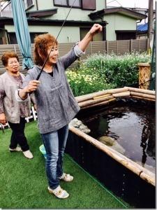 女性が家の庭にある池で釣りをしている様子の写真
